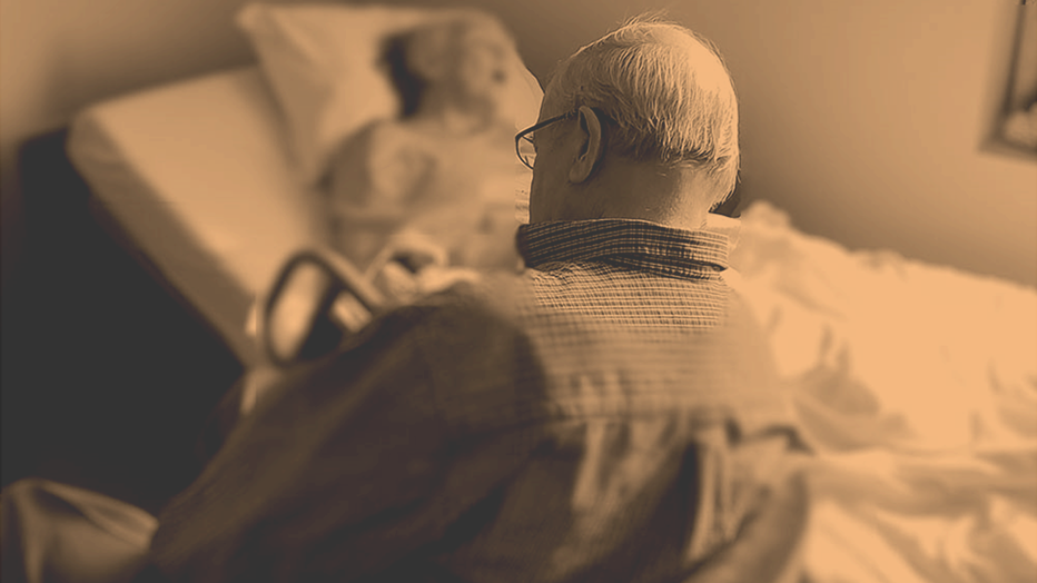 Frail elderly person in wheelchair with caregiver
